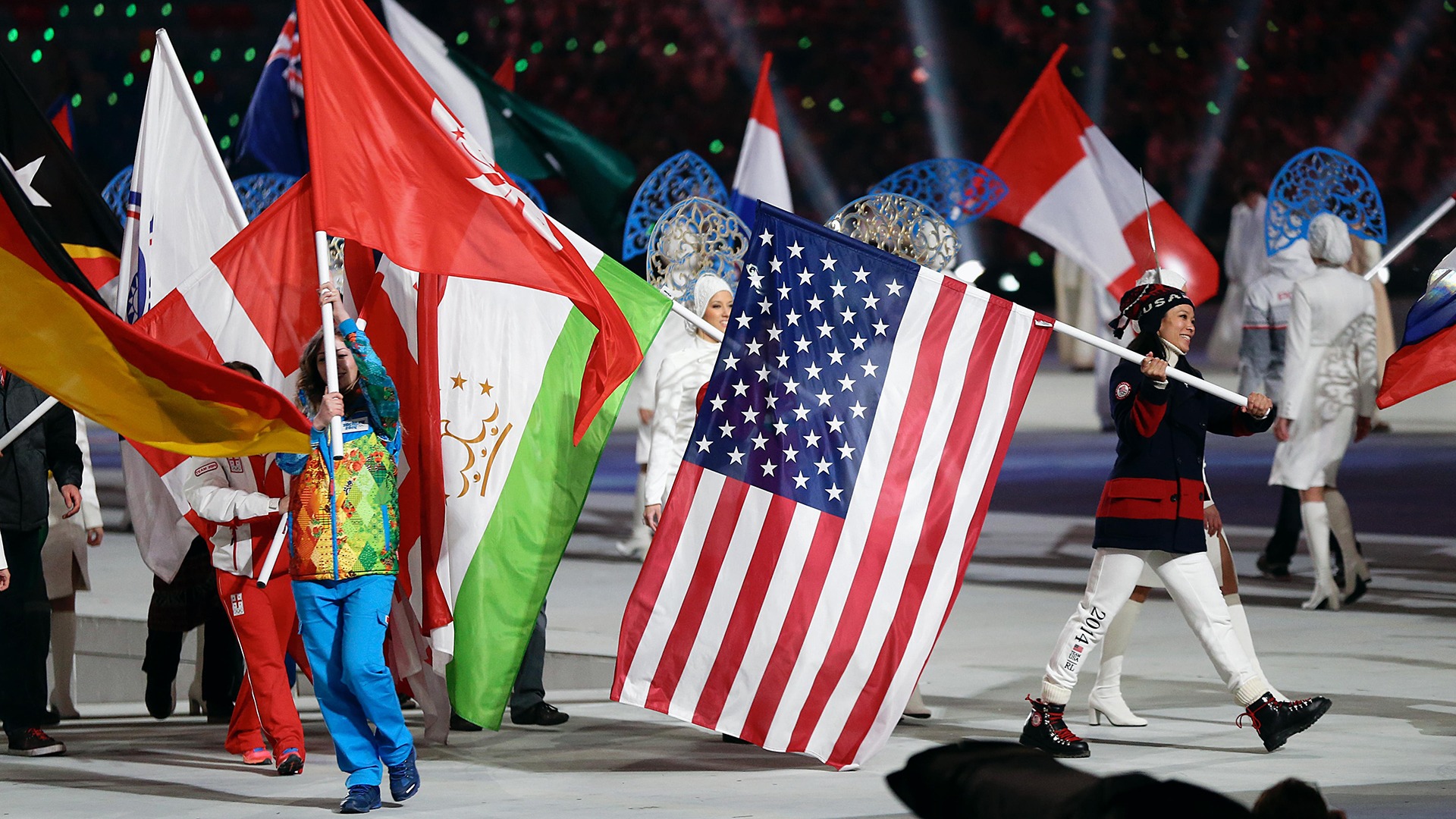 Julie Chu carries the U.S. flag among other nation's flags during the Closing Ceremony