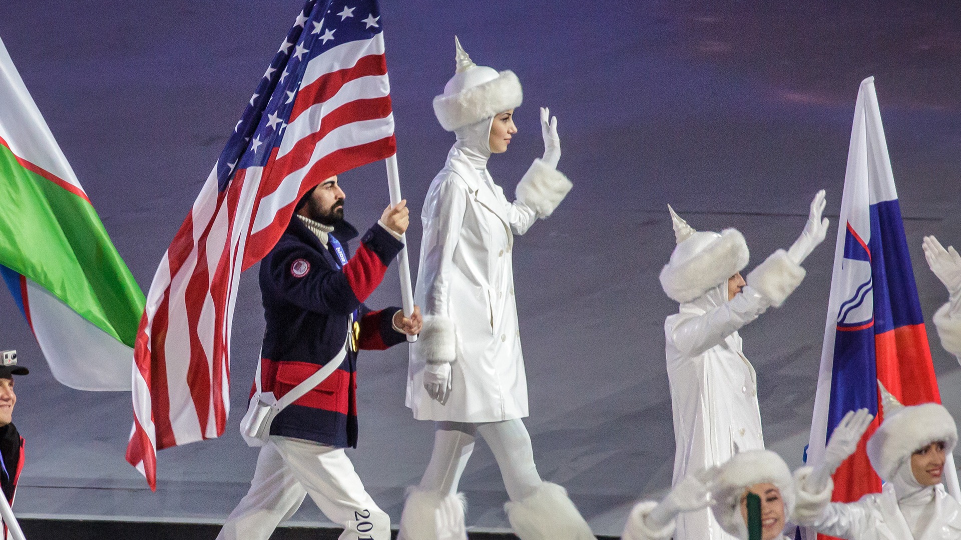 Steve Cash holds aloft the U.S. flag as he walks into the stadium
