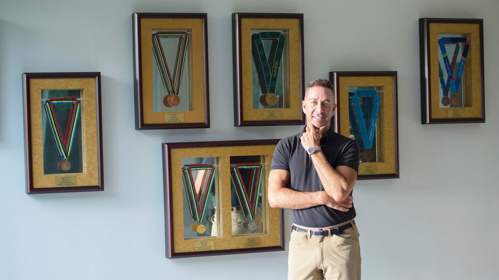 Robert Dover poses in front of his framed medals