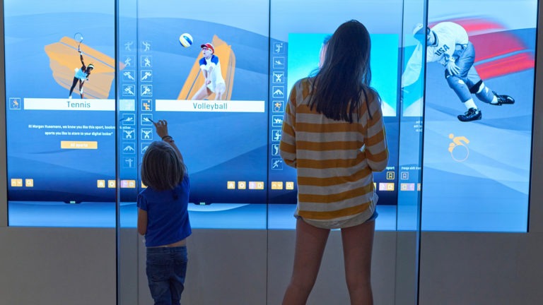 From the back, a woman and a child look at a display in the Museum