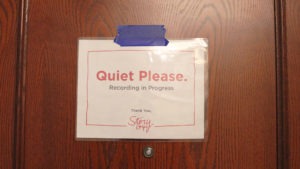 A sign on the outside of a door asks for "Quiet please" while a StoryCorps session is being recorded