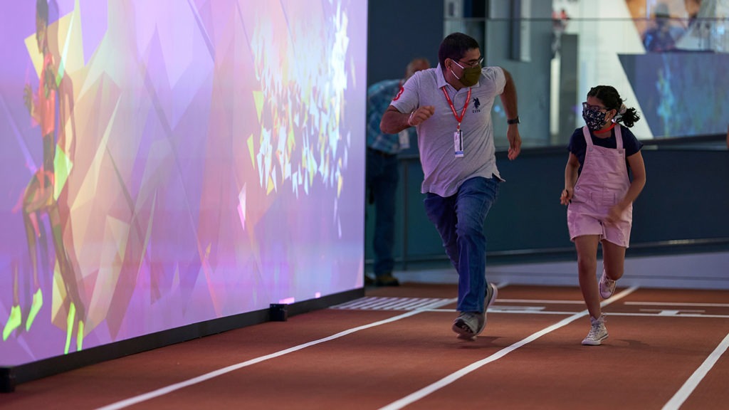 A father and his daughter compete in the 30-meter dash interactive exhibit