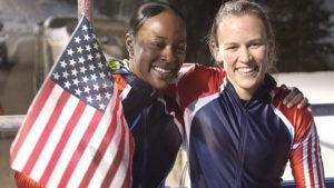 Vonetta Flowers smiles and waves an American flag while posing for a photo with bobsled partner Jill Bakken