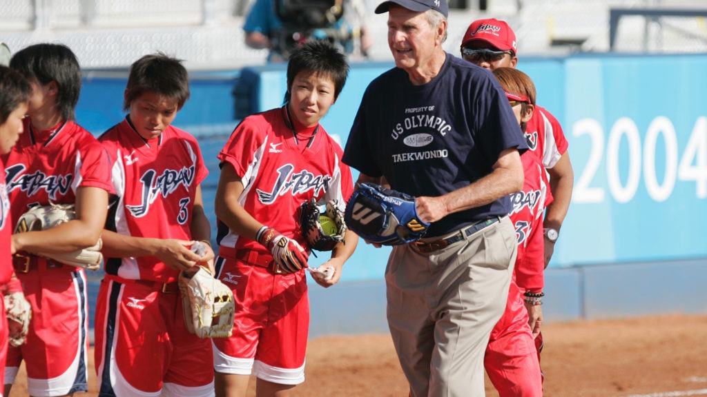George H.W. Bush gets ready to make a throw as the Japanese softball team looks on
