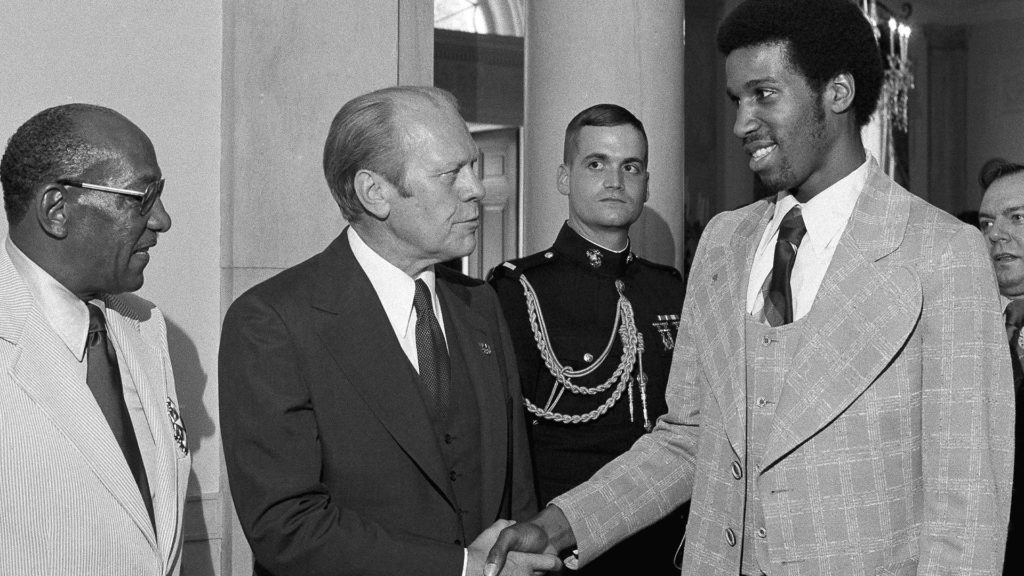 With Jesse Owens to his right, Gerald Ford shakes hands with Adrian Dantley