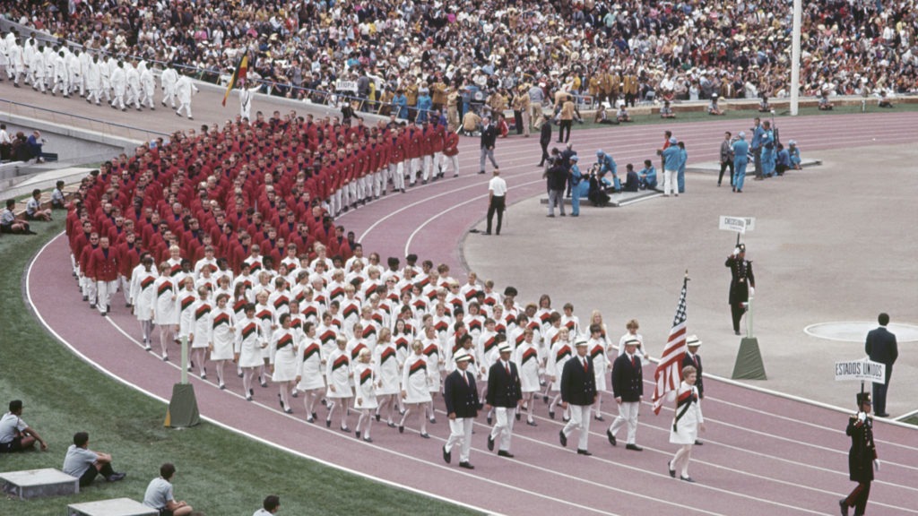 Jan York-Romary is the flag bearer leading Team USA aroudn the track at the Mexico City 1968 Opening Ceremony