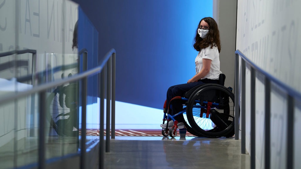 McKenna Geer, sitting in her wheelchair, poses for a photo in the Museum