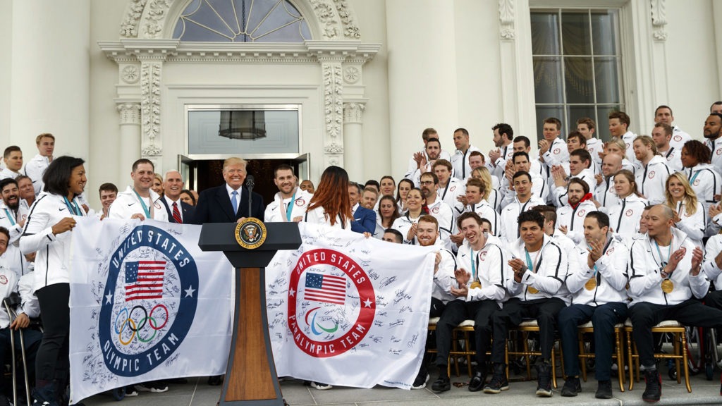 President Donald Trump poses for photographs with signed flags during an event with the United States Olympic and Paralympic Teams at the White House,
