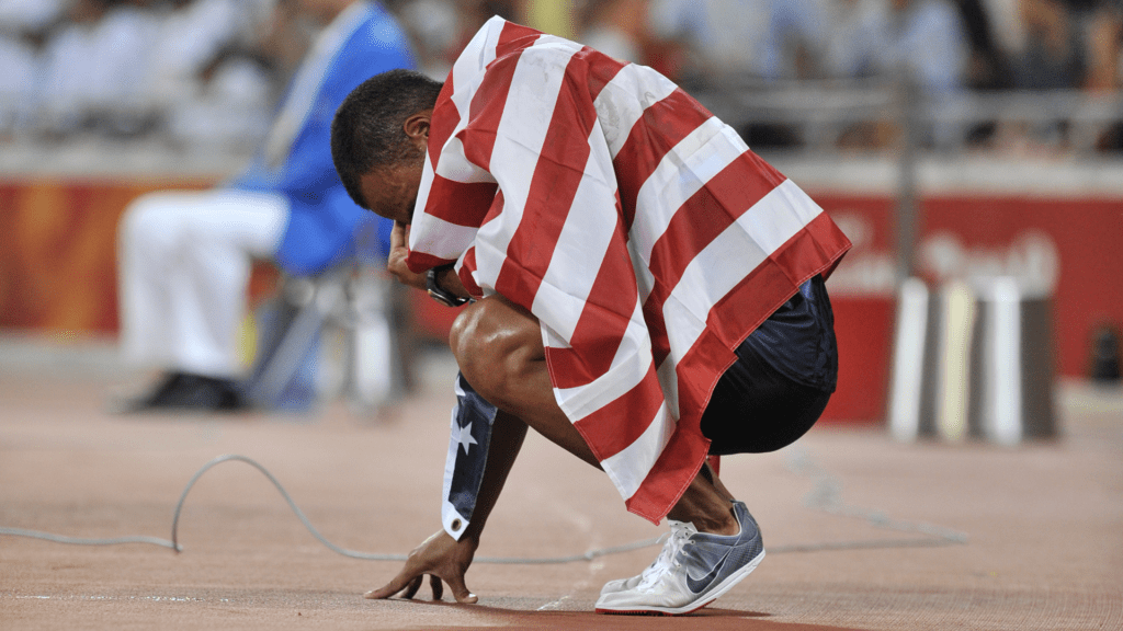 Bryan Clay kneels, overwhelmed with emotion by his victory
