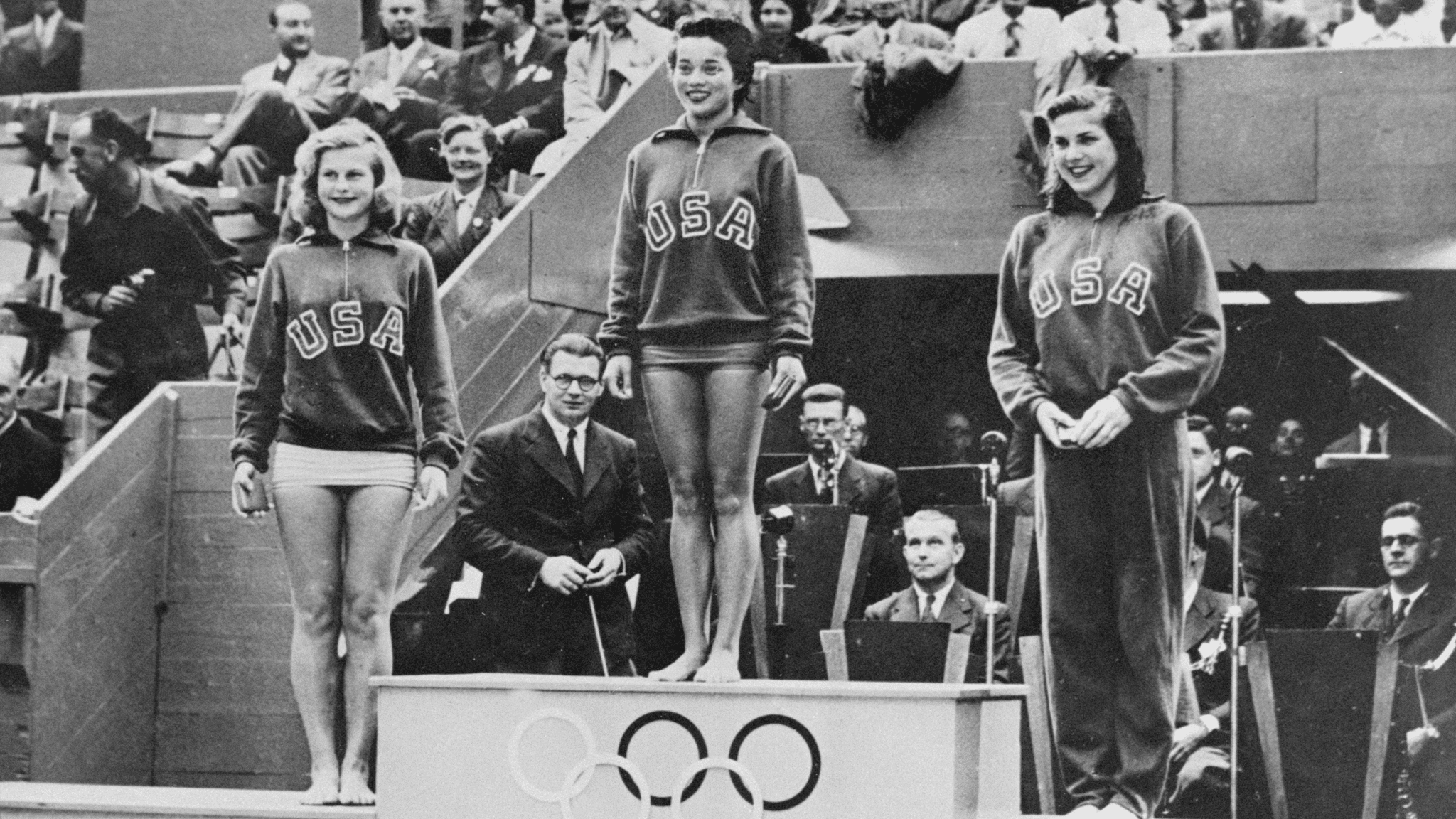 Vicki Draves stands on a podium with two other U.S. divers